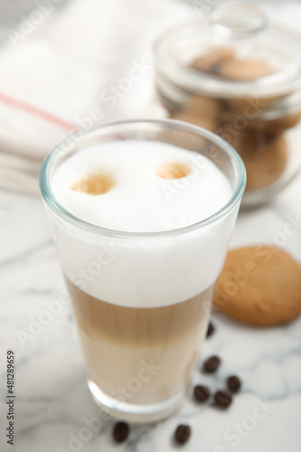 Delicious latte macchiato, cookies and coffee beans on white marble table
