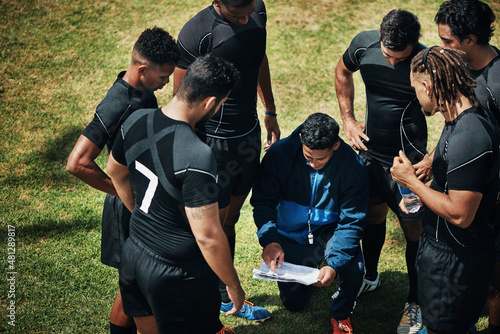 Fototapeta Naklejka Na Ścianę i Meble -  So here's the plan. High angle shot of a handsome young rugby coach addressing his team on the field during the day.