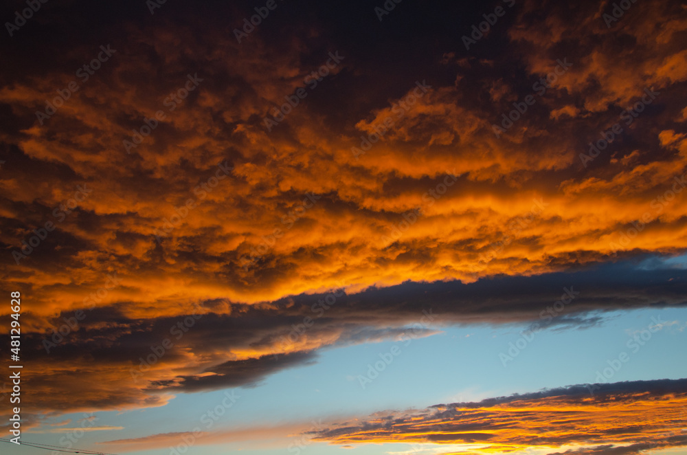 Lush, heavy clouds, painted orange by the sun at sunset. Texture.