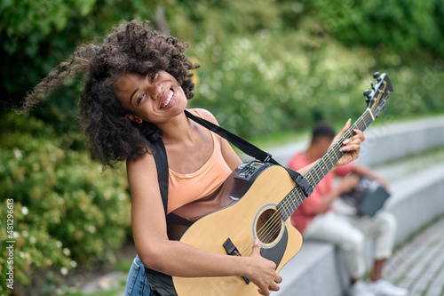 Happy woman with guitar and man behind in park