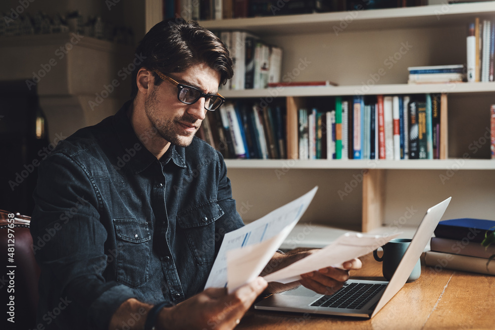 Sorting out some paperwork today. Shot of a handsome young businessman going over paperwork in his office at home. Sorting out some paperwork today. Shot of a handsome young businessman going over paperwork in his office at home.