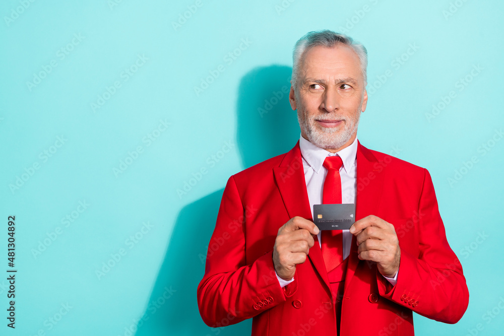 Photo of thoughtful retired man wear red three piece suit holding bank card empty space isolated turquoise color background Photo of thoughtful retired man wear red three piece suit holding bank card empty space isolated turquoise color background