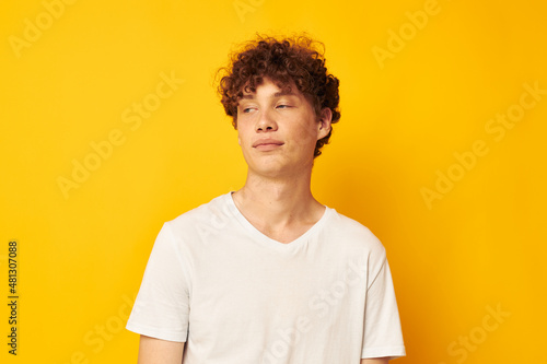 curly red-haired guy in a white t-shirt on a yellow background