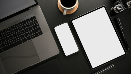 Modern dark workspace with laptop computer, smartphone and digital tablet mockup