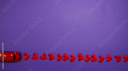 A red toy car rides on a purple background. Stop motion animation.