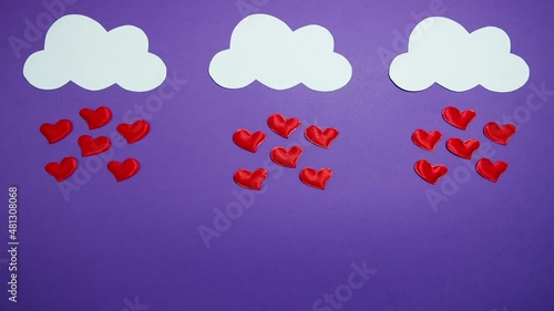 White clouds with a rain of red hearts float on a purple background. Stop motion animation.