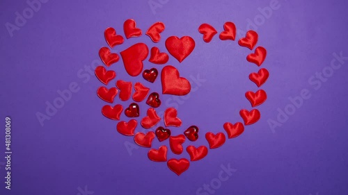 A red heart slowly appears on a purple background. Stop motion animation.