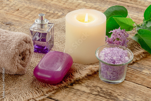 Towel  sea salt  candle and lilac flowers on wooden background.