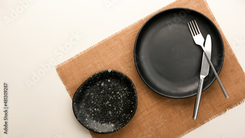 Empty patterned black plate, silverware on white table. photo