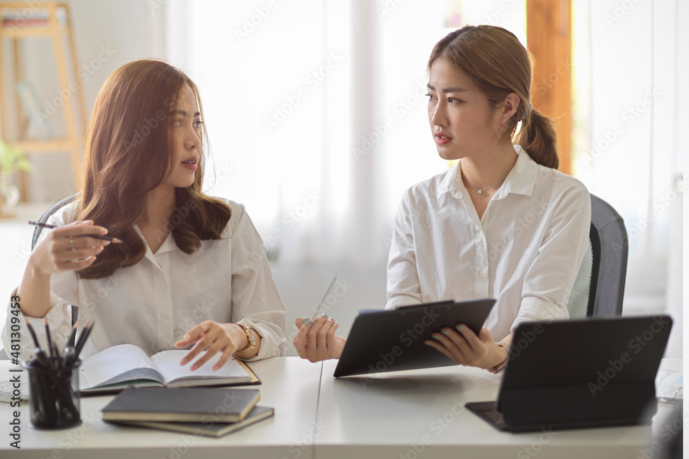 Two Asian businesswomen are discussing and planning business strategy Two Asian businesswomen are discussing and planning business strategy