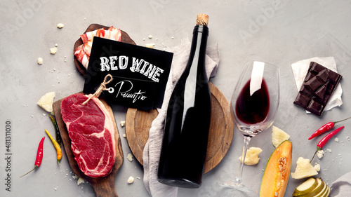 Red wine Primitivo with appetizers on gray background.