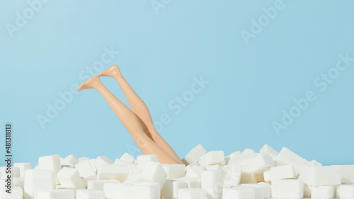 Female doll diving in sugar cubes. Stop sugar adiction concept.