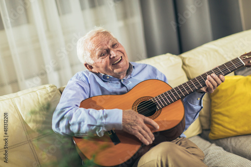 Senior man playing guitar in the living room