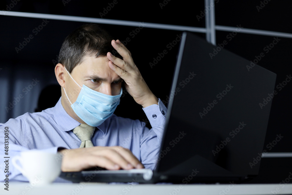 Worried man in face mask and office clothes looking focused at laptop display. Concept of solving a difficult task Worried man in face mask and office clothes looking focused at laptop display. Concept of solving a difficult task