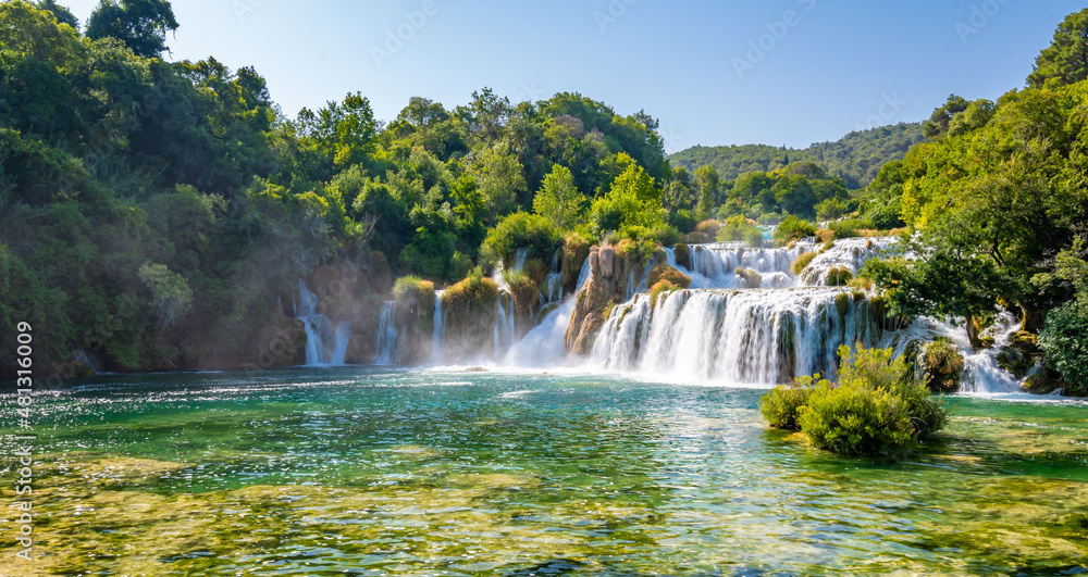 Obraz premium Waterfalls at Skradinski Buk, national nature park Krka, Croatia. Flowing water in beautiful nature, green plants and trees. Sunny summer day.