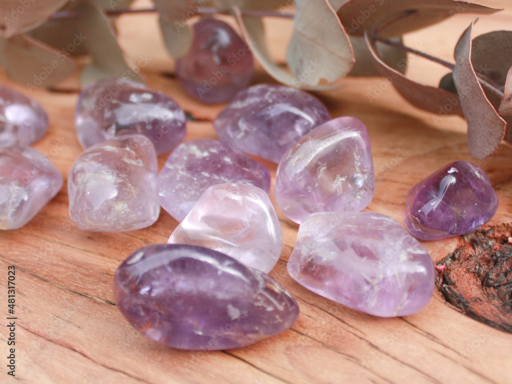 amethyst purple crystal tumbled semi precious stone, senitransparent rock, on raw natural wood with leaves and flowers babies breath amethyst purple crystal tumbled semi precious stone, senitransparent rock, on raw natural wood with leaves and flowers babies breath