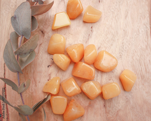 Vászonkép Orange aventurine crystal tumbled rock, semiprecious stone, on raw natural wood