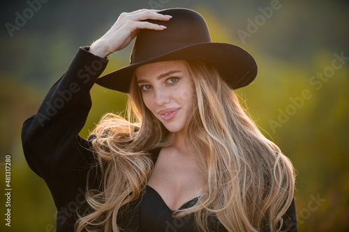 Beautiful girl face closeup, outside portrait of young woman in fashion brim black hat. Summer romantic casual woman. Lifestyle, walk outdoors, enjoying life, positivity. © Volodymyr