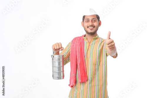 Young indian common man in traditional wear holding tiffin box in hand on white background. photo