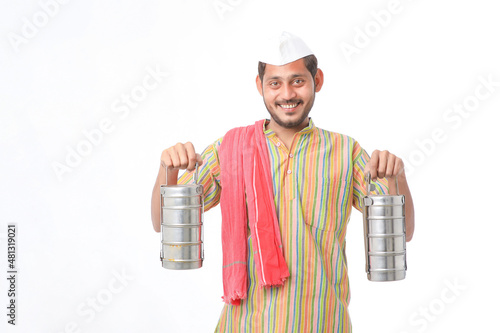 Young indian common man in traditional wear holding tiffin box in hand on white background. photo