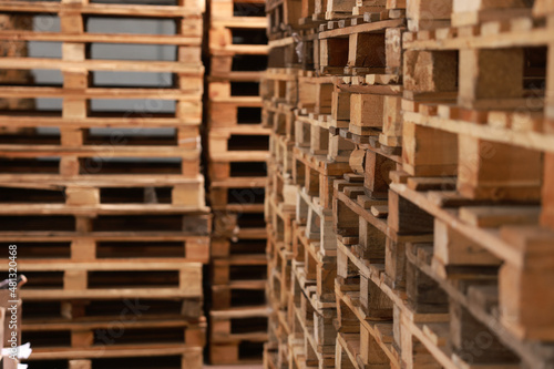 Many empty wooden pallets stacked in warehouse  closeup. Space for text
