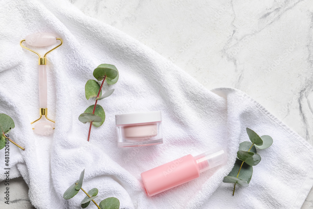 Face massage roller with cosmetic products and towel on white background Face massage roller with cosmetic products and towel on white background