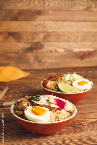 Healthy quinoa bowls with egg on wooden background