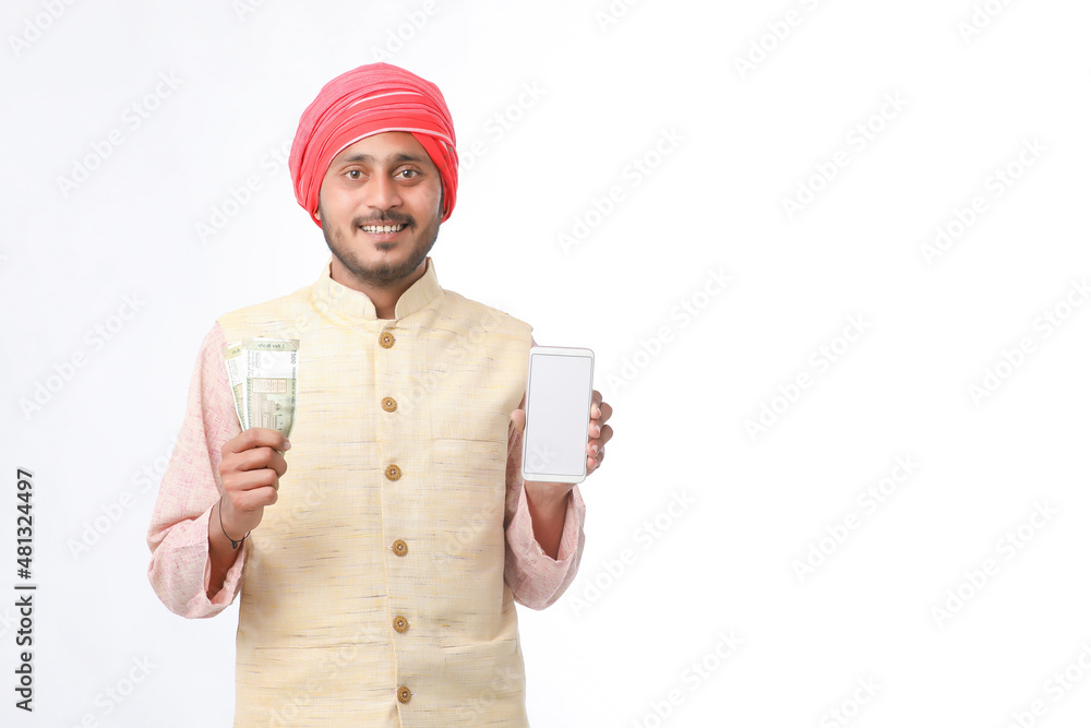 Young indian farmer showing smartphone and money on white background. Young indian farmer showing smartphone and money on white background.