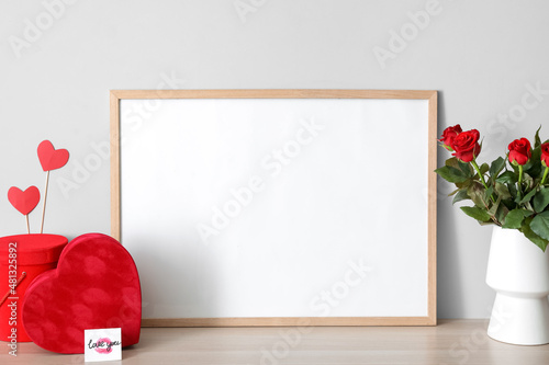 Gifts for Valentine's Day and flowers with empty photo frame on table in room