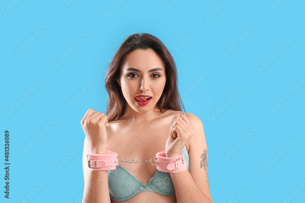 Naklejka premium Young woman with handcuffs from sex shop on blue background