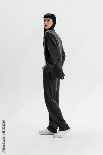 Studio photoshoot of a young brunette woman wearing casual clothing against a white background.  Natural makeup and hairstyle