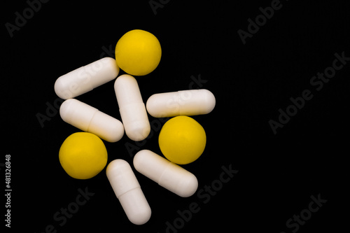 Medicines in capsules and drops. Isolated top view on black background. Copy space.