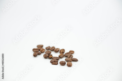 Einzelne geröstete Kaffeebohnen liegen nebeneinander vor einem weißen Hintergrund