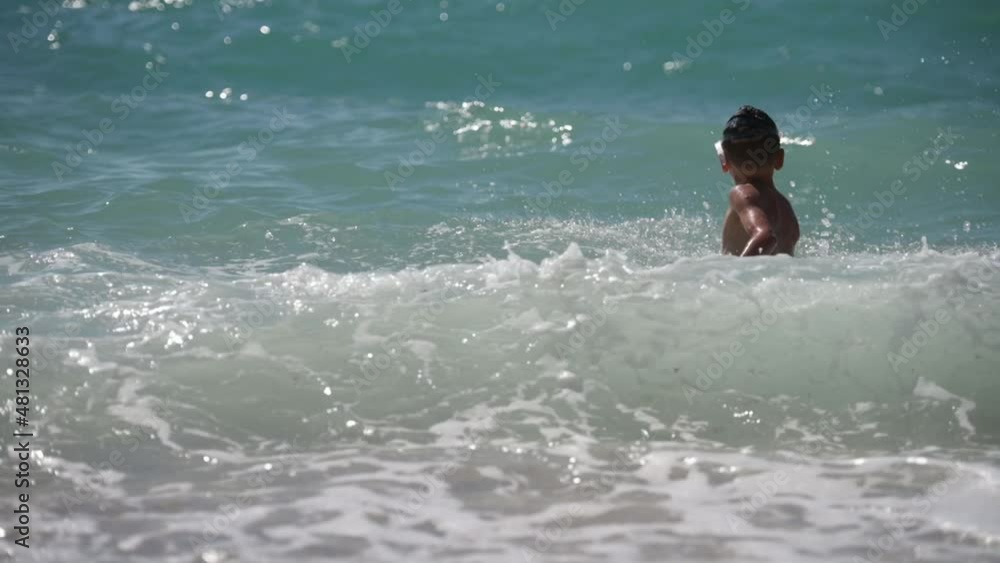 active healthy little boy in diving mask playing with waves in stormy summer sea in slow motion during holiday vacation travel leisure activity active healthy little boy in diving mask playing with waves in stormy summer sea in slow motion during holiday vacation travel leisure activity