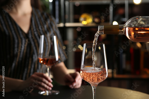 Pouring rose wine from bottle into glass indoors, closeup Fototapet
