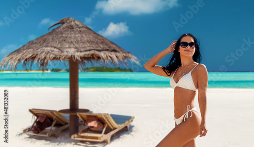 people, summer and swimwear concept - happy smiling young woman in bikini swimsuit over tropical beach background in french polynesia