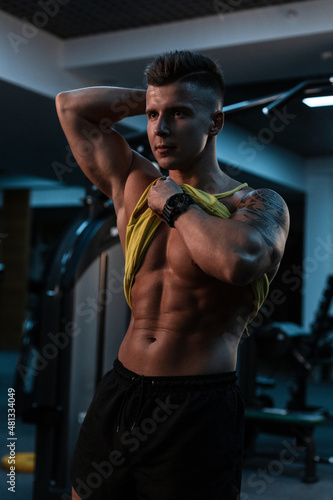 handsome young bodybuilder man model with a muscular abdominal press trains in the gym