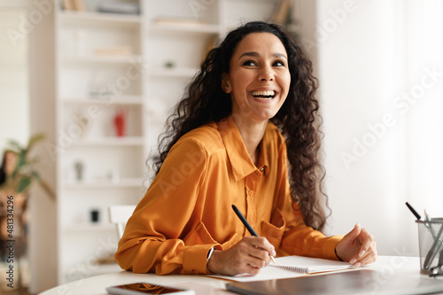 Happy Lady Taking Notes Sitting At Desk Holding Pen Indoor