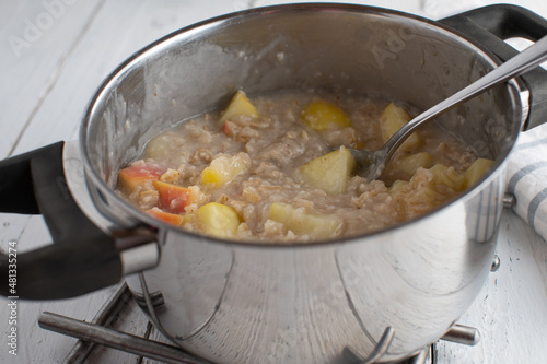 Pot with fresh cooked oatmeal porridge, made with water and apples