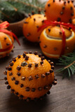 Pomander balls made of tangerines with cloves and fir branches on wooden table, closeup