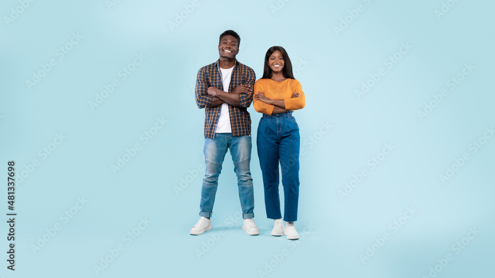 Confident couple standing with folded arms at blue studio background Confident couple standing with folded arms at blue studio background