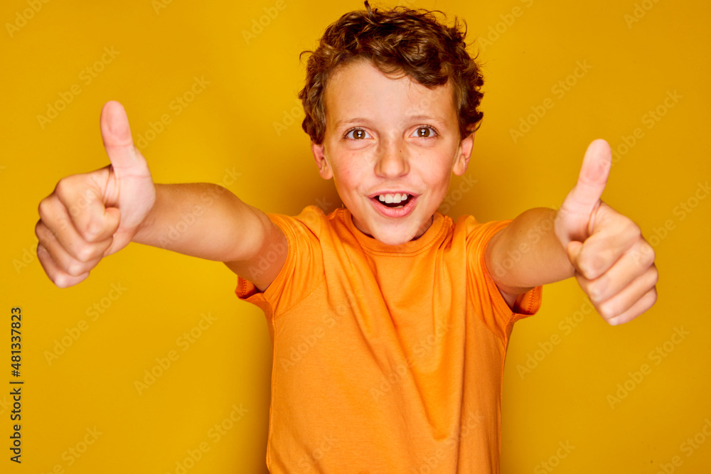 Petit garçon plein de joie et d'énergie sous la lumière d'un studio lumineux de couleur jaune Petit garçon plein de joie et d'énergie sous la lumière d'un studio lumineux de couleur jaune