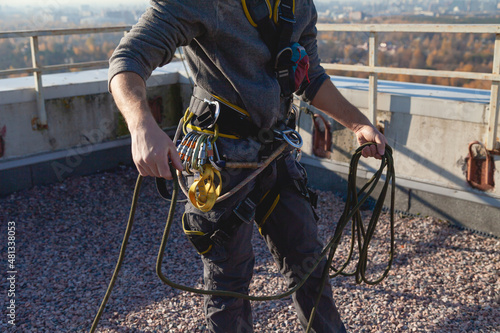 Worker in climbing gear is getting ready to hang out