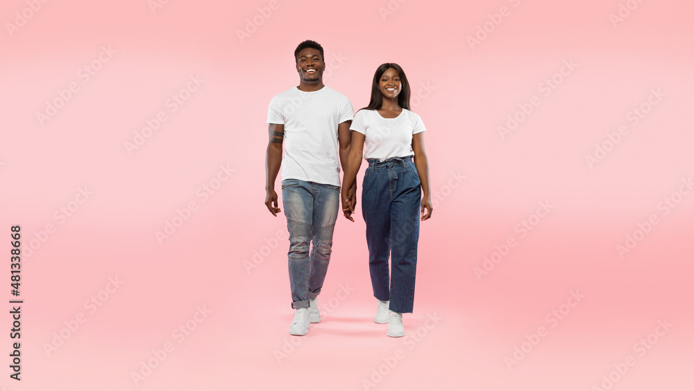 Confident couple walking to camera at pink studio background Confident couple walking to camera at pink studio background