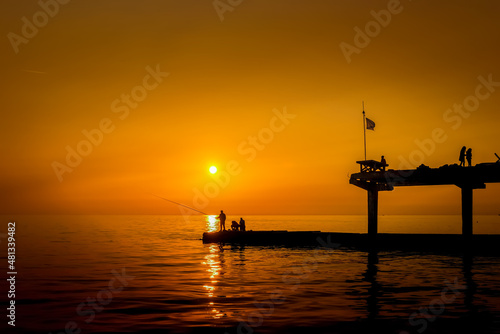Fishermen on the seashore against the backdrop of sunset.