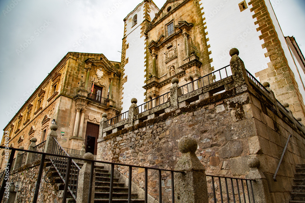 Fachada y acceso a Iglesia de torres de piedra con fachada blanca en Cáceres