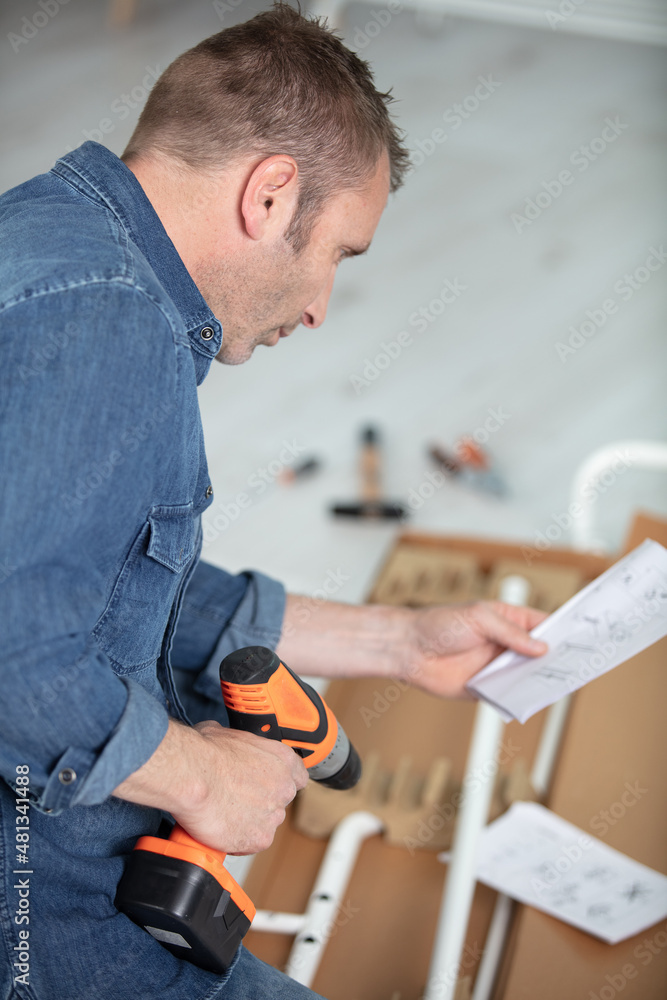 man putting together self assembly furniture in new home