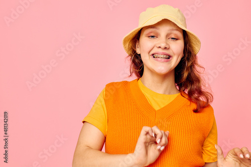 portrait of a young woman in an orange sweater in yellow hat hand gesture cropped view unaltered