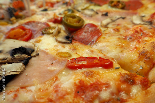 pizza close-up with cheese, pepperoni, bacon and herbs. side view. high-calorie food. italian cuisine