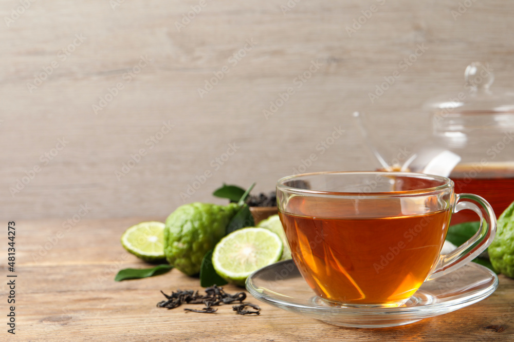 Glass cup of tasty bergamot tea and fresh fruits on wooden table, space for text Glass cup of tasty bergamot tea and fresh fruits on wooden table, space for text